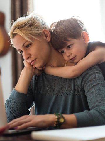 I love you mom! A cute little boy hugging his mom tightly while she is working.