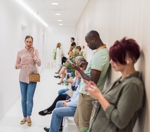 Scene of a medical facility waiting room packed full of people waiting